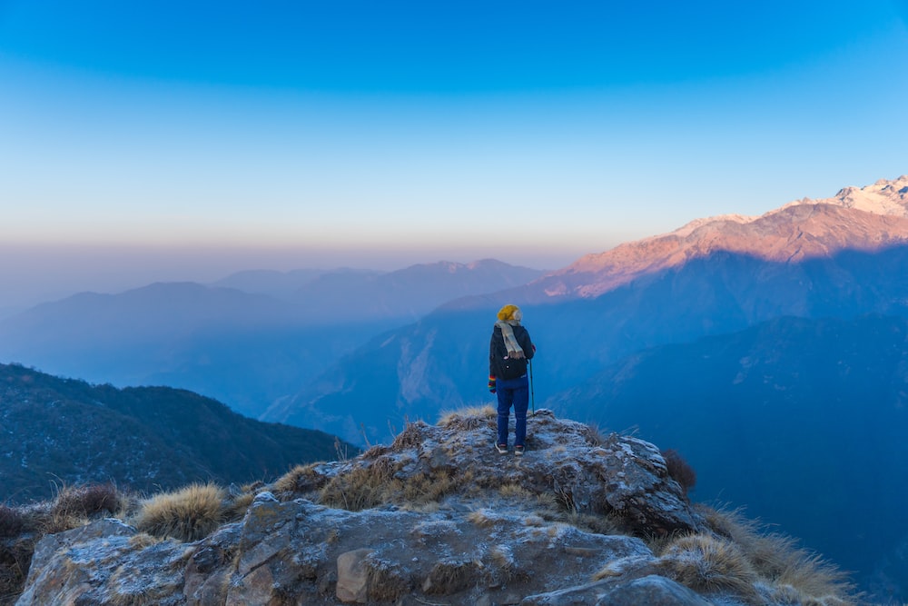man in black jacket standing on rock mountain during daytime