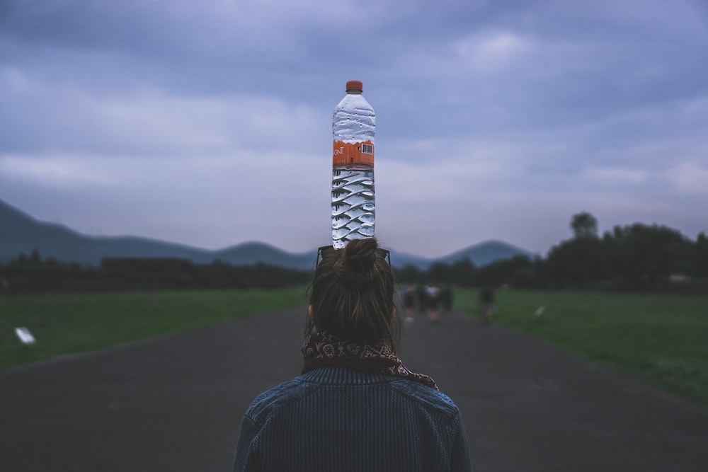 woman putting a clear plastic bottle on her head
