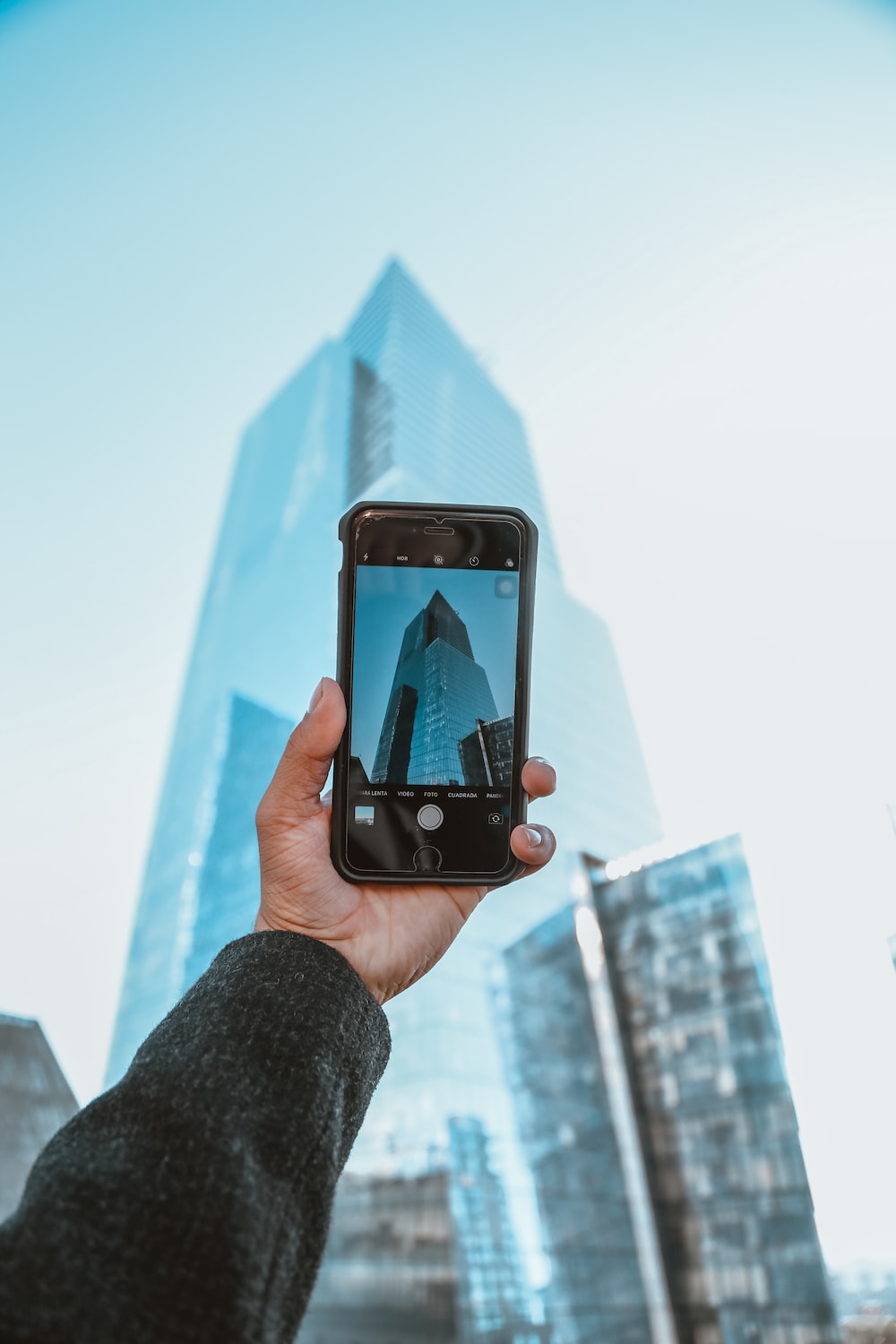 person holding black iphone 5 taking photo of high rise building